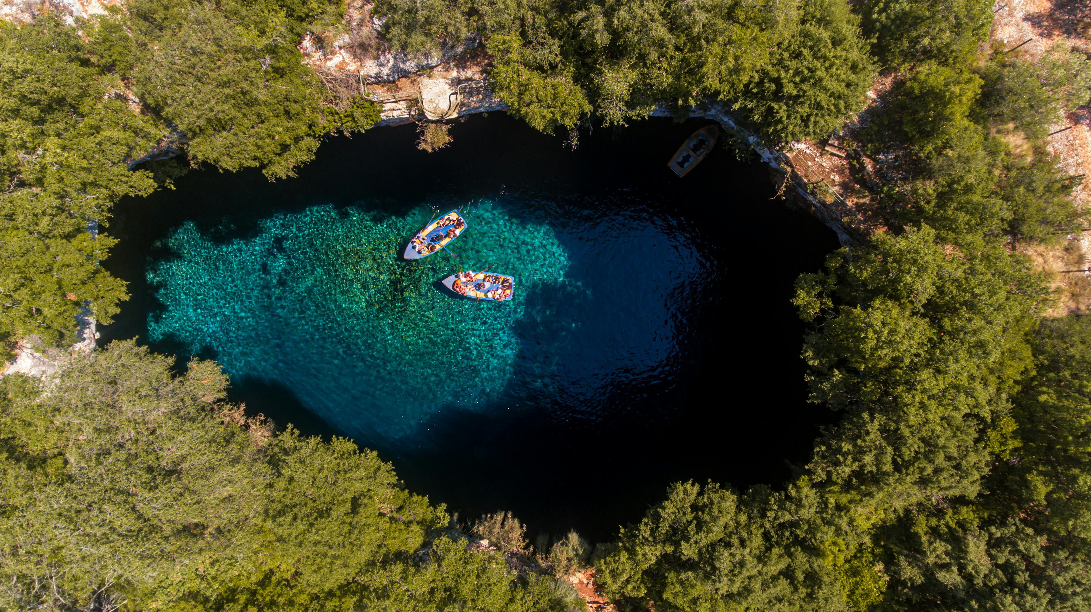 一艘令人惊叹的航拍船停泊在清澈的绿松石湖上，四周绿树环绕，是自然与旅行概念的理想之选