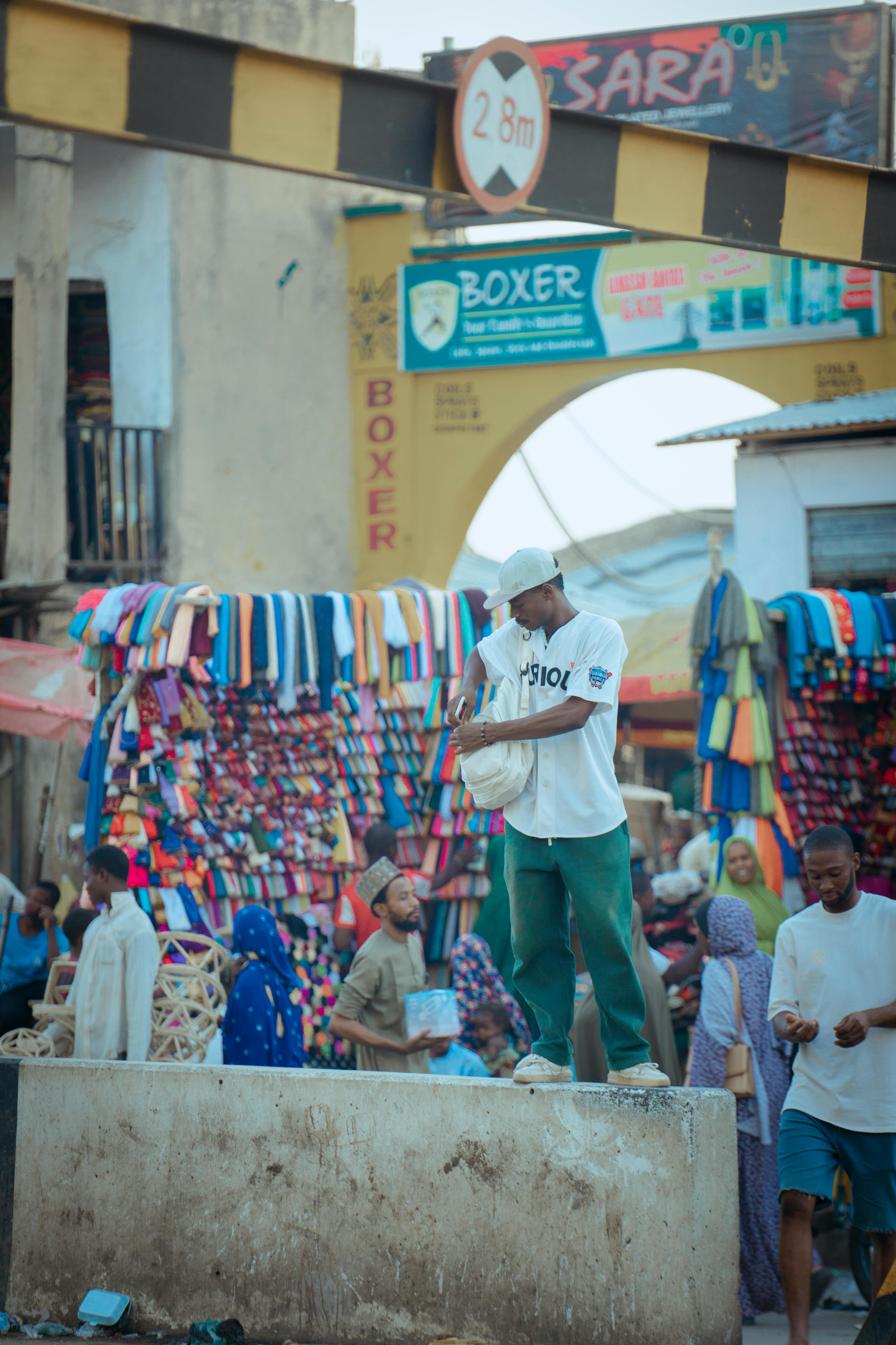 A busy market street with people shopping and vibrant textile displays.