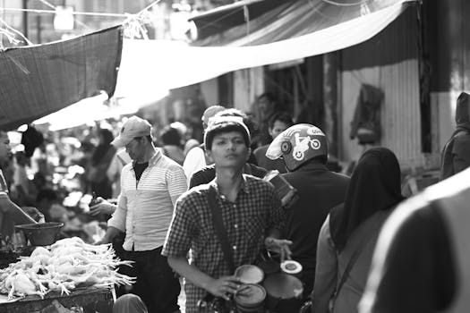 A bustling black and white market scene in West Java, Indonesia, showcasing vendors and shoppers.