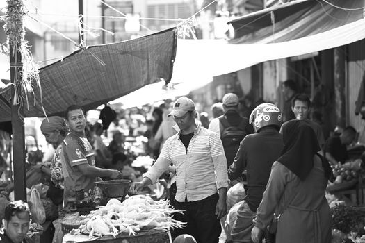 Black and white image of a lively street market scene in Bogor, showcasing local vendors and shoppers.