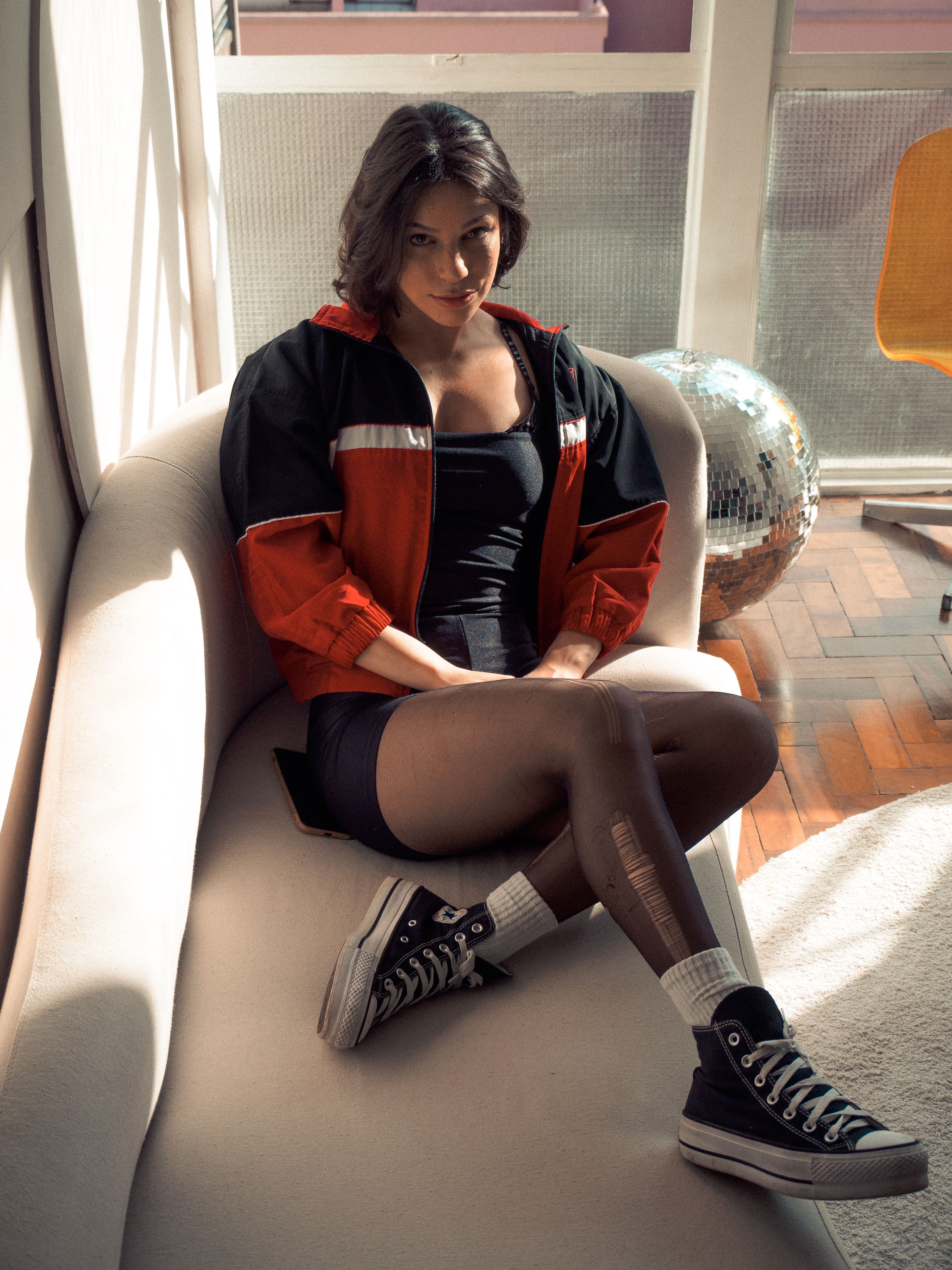 Casual portrait of a woman in sporty attire sitting on a sofa in natural light.