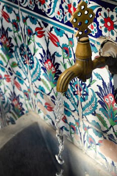 A decorative fountain tap with flowing water set against vibrant, intricately patterned tiles.