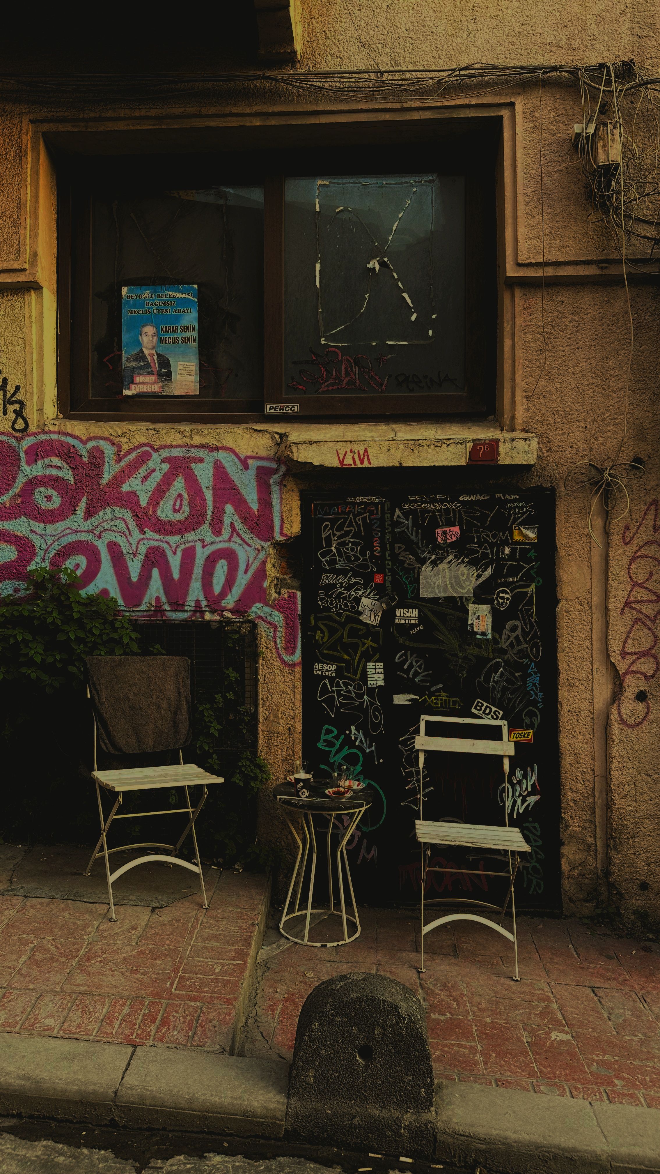 Chairs outside a graffiti-covered urban building create a unique artistic scene.
