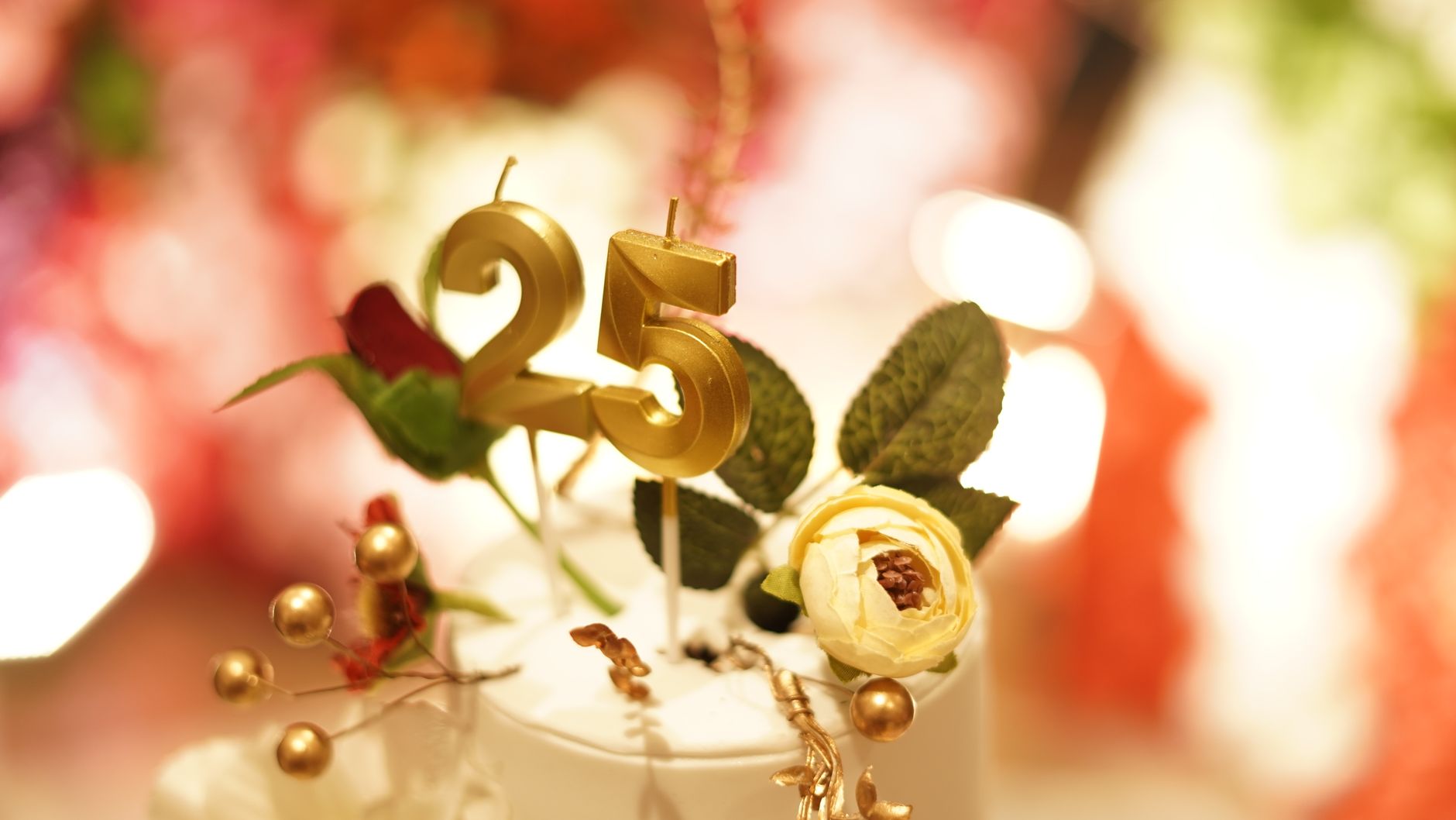 Close-up of a 25th wedding anniversary cake topper with golden decoration and flowers.