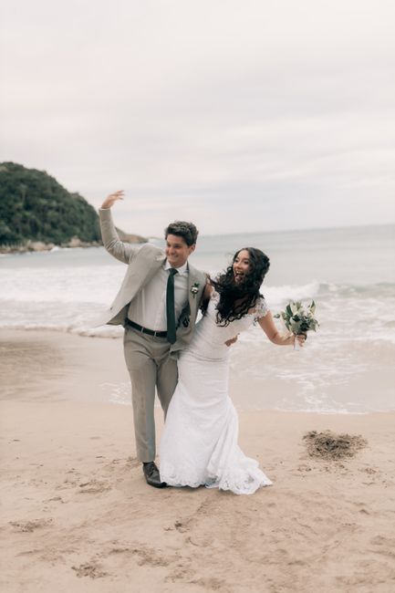 Happy couple in wedding attire celebrating on a scenic beach location.