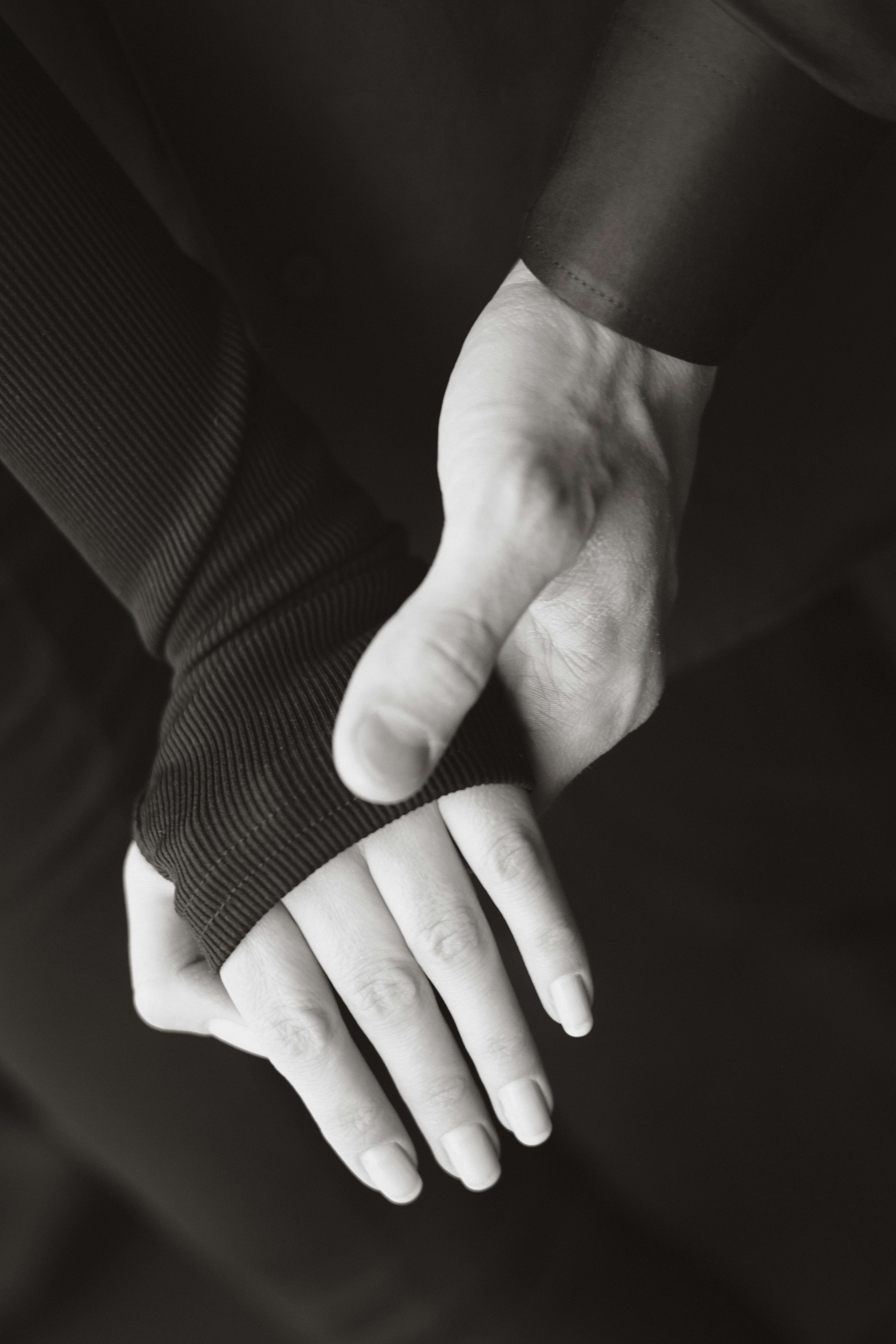 Kostenlos Ein künstlerisches Schwarzweißfoto eines Paares, das Händchen hält und Liebe und Verbundenheit symbolisiert. Stock-Foto