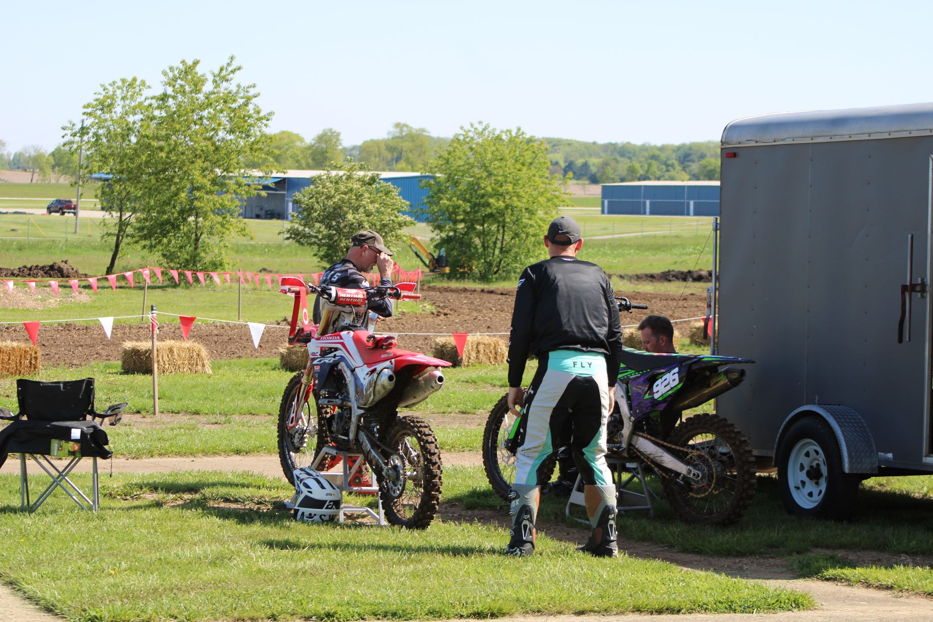 Motocross riders and enthusiasts preparing bikes and equipment at an outdoor event in Carroll, Ohio.