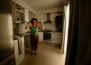 Person standing in a kitchen, playfully using a blindfold.