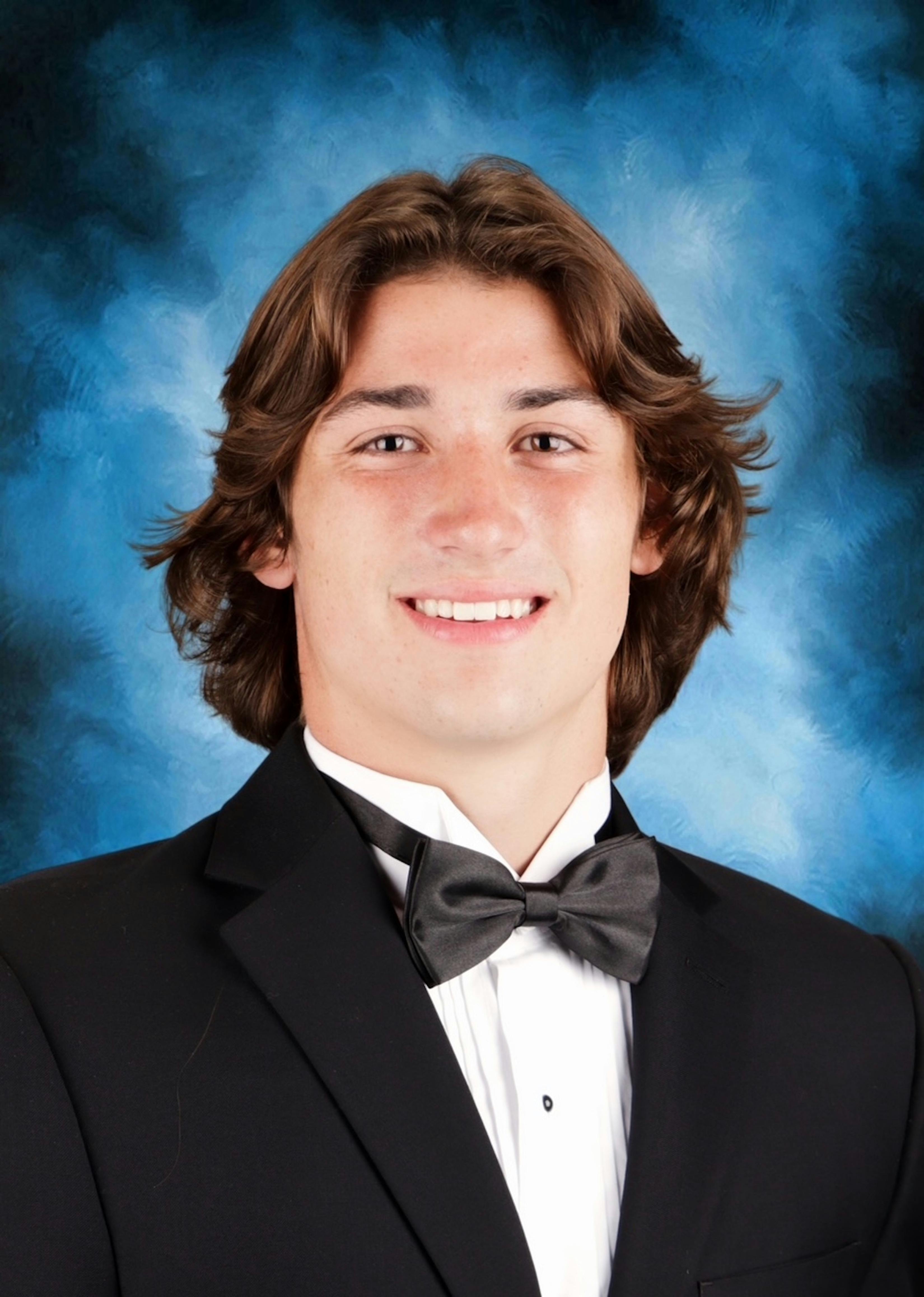 Portrait of a young man in a tuxedo with a blue background, perfect for formal settings.