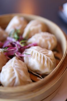 Delicious steamed dumplings garnished with herbs in a bamboo basket, perfect for Asian cuisine lovers.