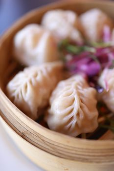 Delicious steamed dumplings served in a bamboo basket with vibrant garnish.