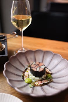 Elegant gourmet dish paired with white wine in upscale restaurant setting.