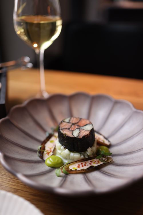 Free A gourmet dish elegantly plated with a glass of white wine in a fine dining restaurant. Stock Photo