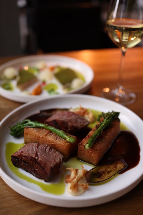 Free Elegant beef dish with gourmet presentation, paired with white wine for a fine dining experience. Stock Photo