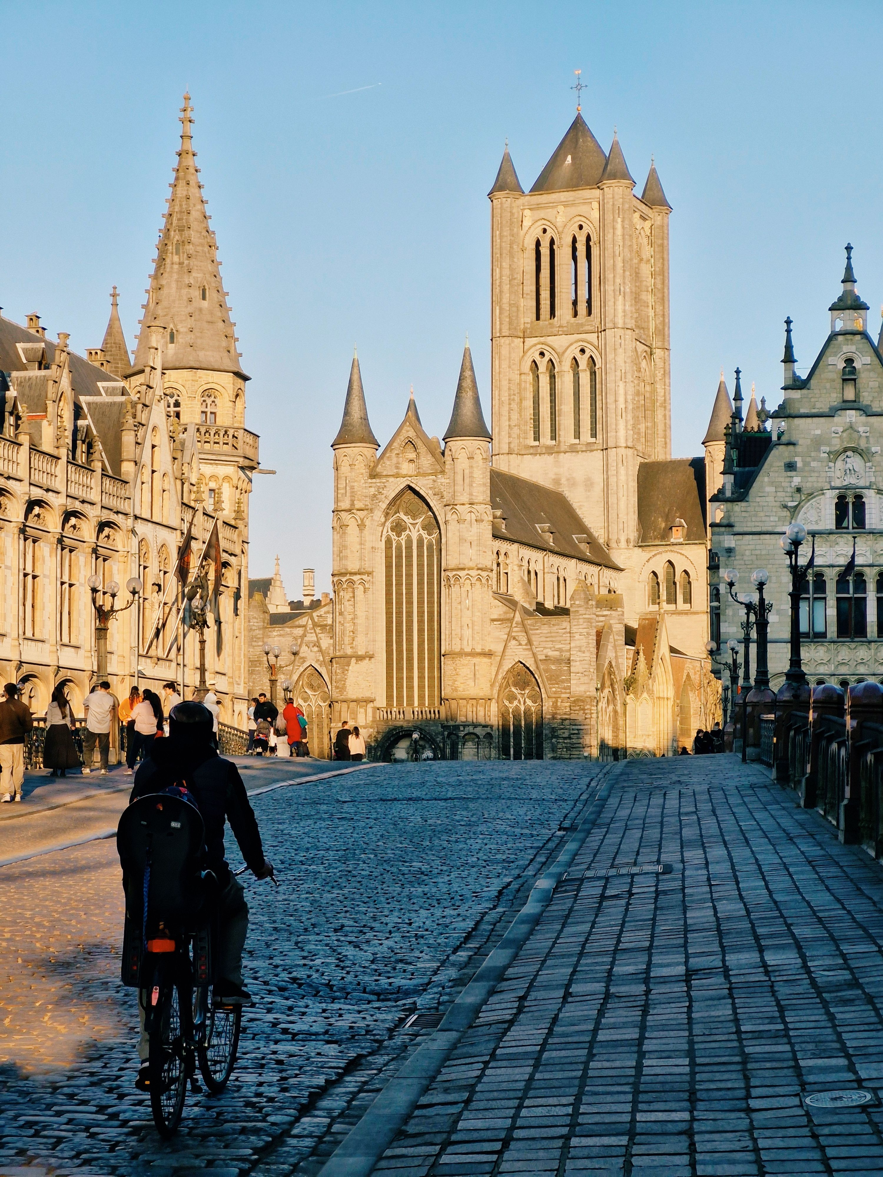 Explore the historic charm of Ghent's medieval architecture as a cyclist passes by at dusk.