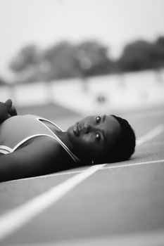 Artistic black and white photo of a woman lying down on an outdoor surface, creating a serene and elegant portrait.
