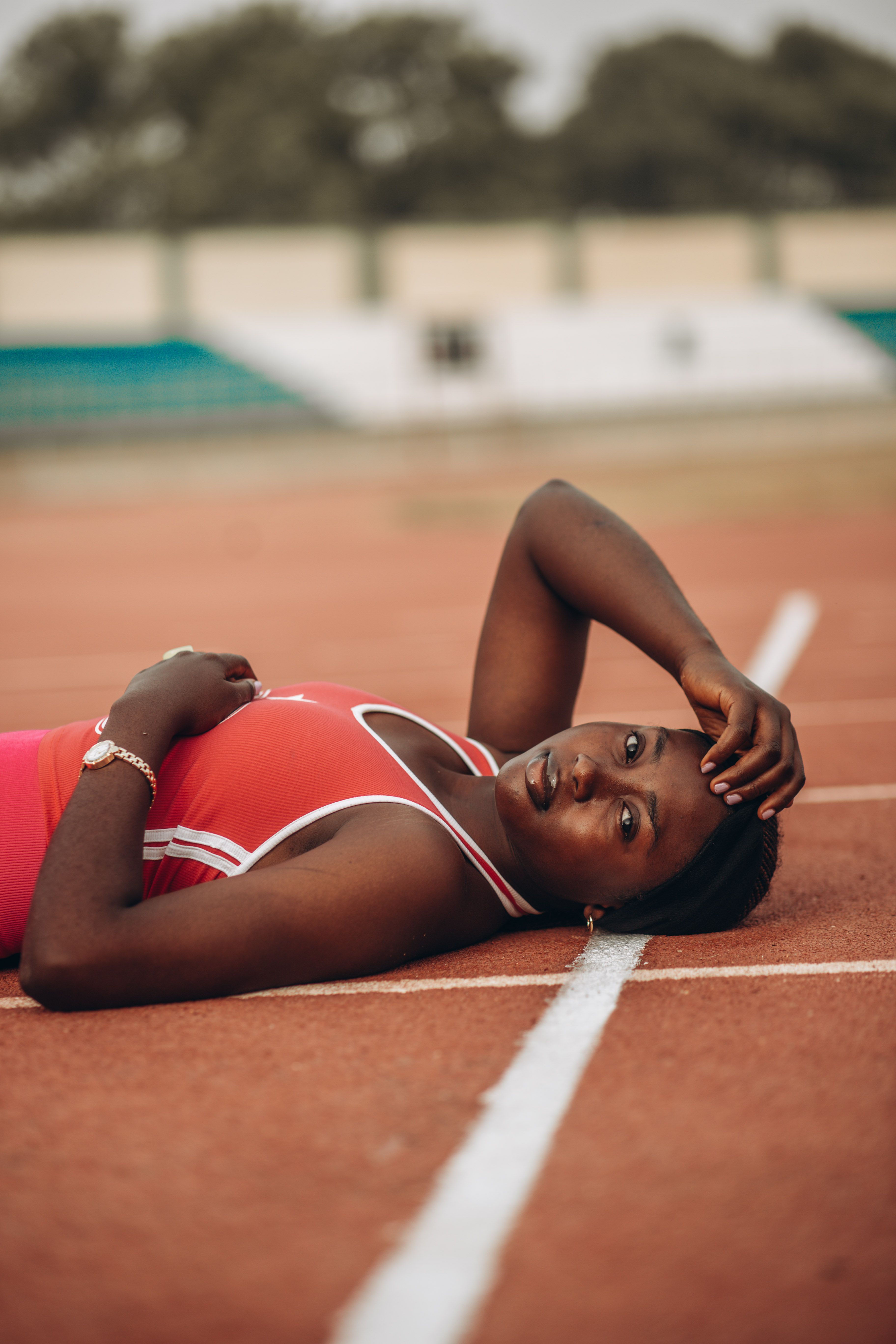 Woman in sportswear relaxing on a running track, showcasing stamina and fitness.