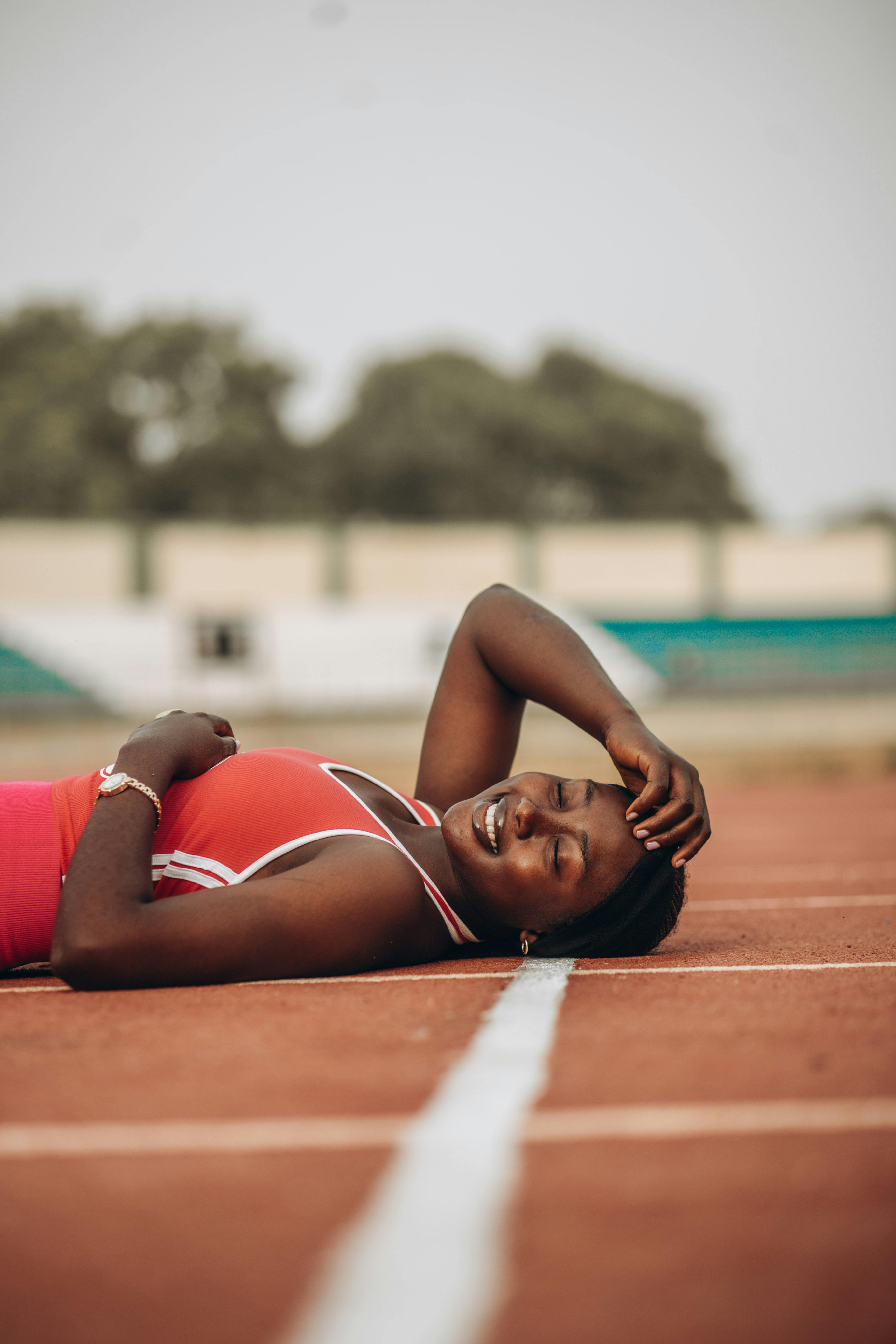 Smiling female athlete taking a break on a running track with a serene expression.