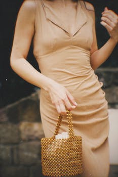 Stylish woman in a beige dress with a chic beaded handbag, creating a vintage fashion vibe.
