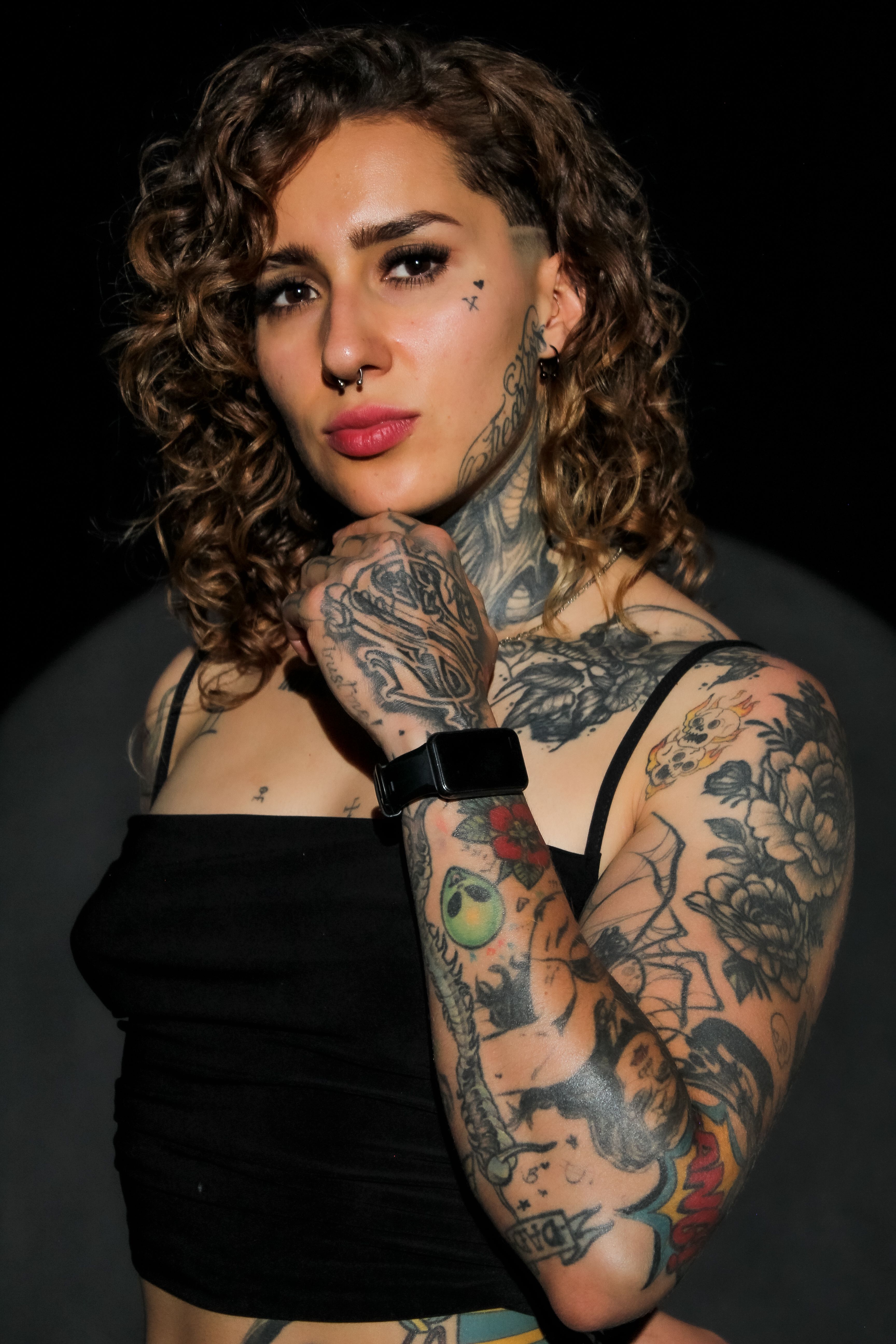 Portrait of a tattooed woman in a studio setting showcasing body art and expression.