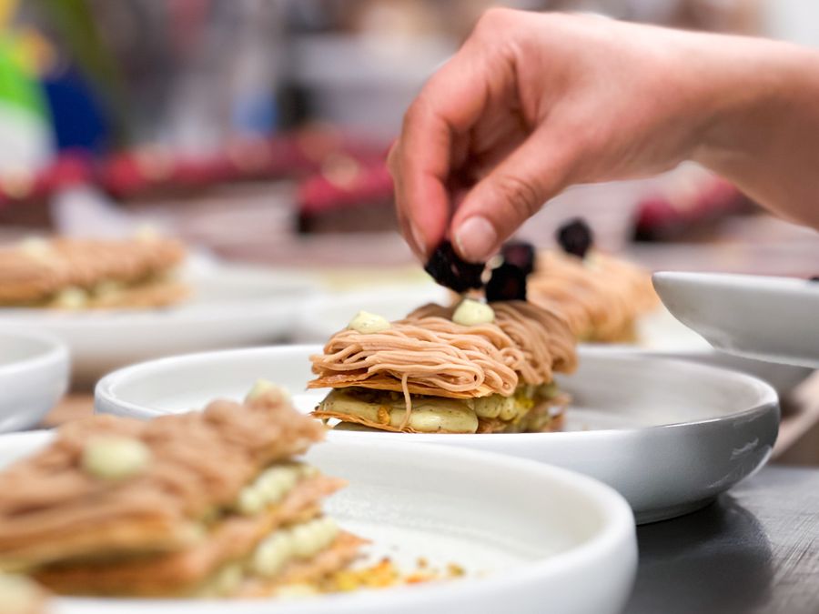 A chef finishing a plated pastry in a restaurant kitchen — photo by Sofia Lonshakova on Pexels