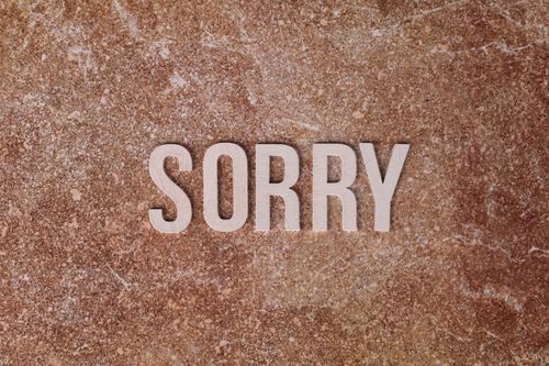 Free Wooden letters spell 'SORRY' on a textured brown stone background, expressing apology. Stock Photo