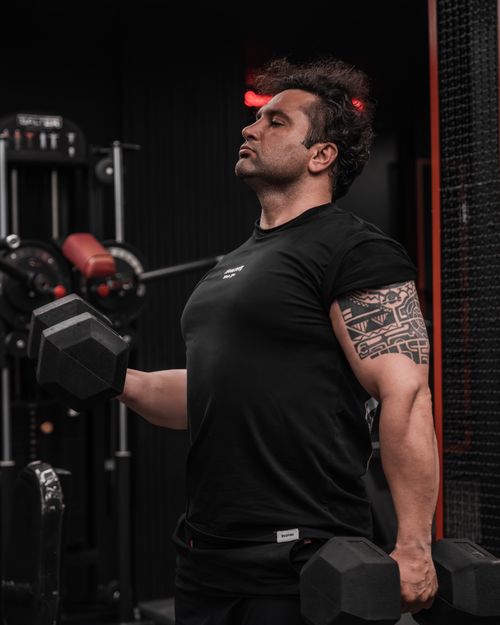 Free Focused man lifting dumbbells in gym, highlighting strength and dedication. Stock Photo