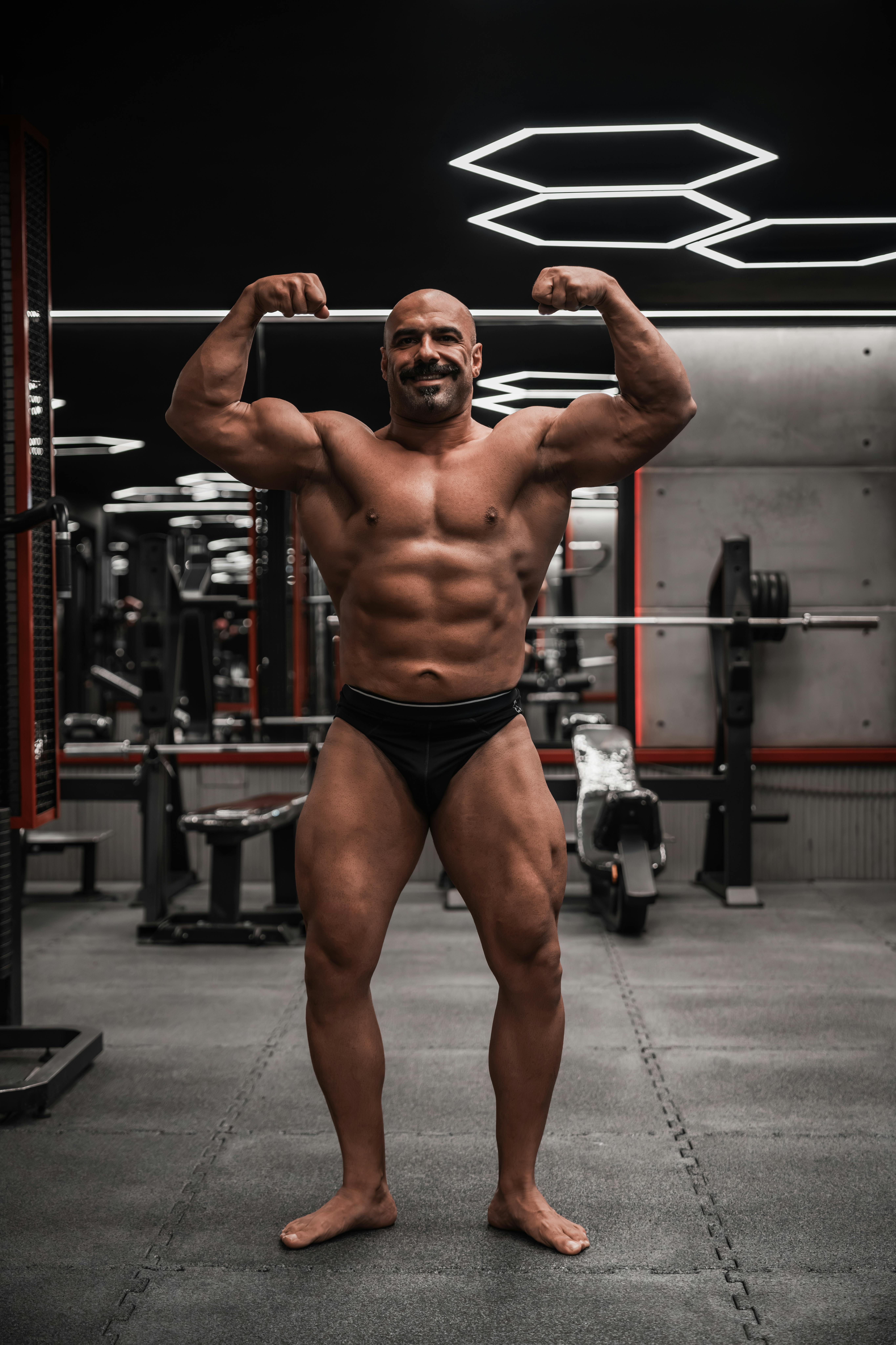 Strong bodybuilder flexing muscles in a gym setting. Fitness and strength concept.