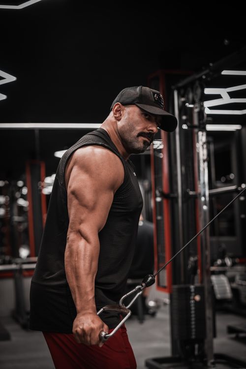 Free Man intensely focused during cable workout in a sleek and modern gym environment. Stock Photo