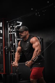 Strong male athlete working out on a cable machine in a gym setting, showcasing strength and fitness.