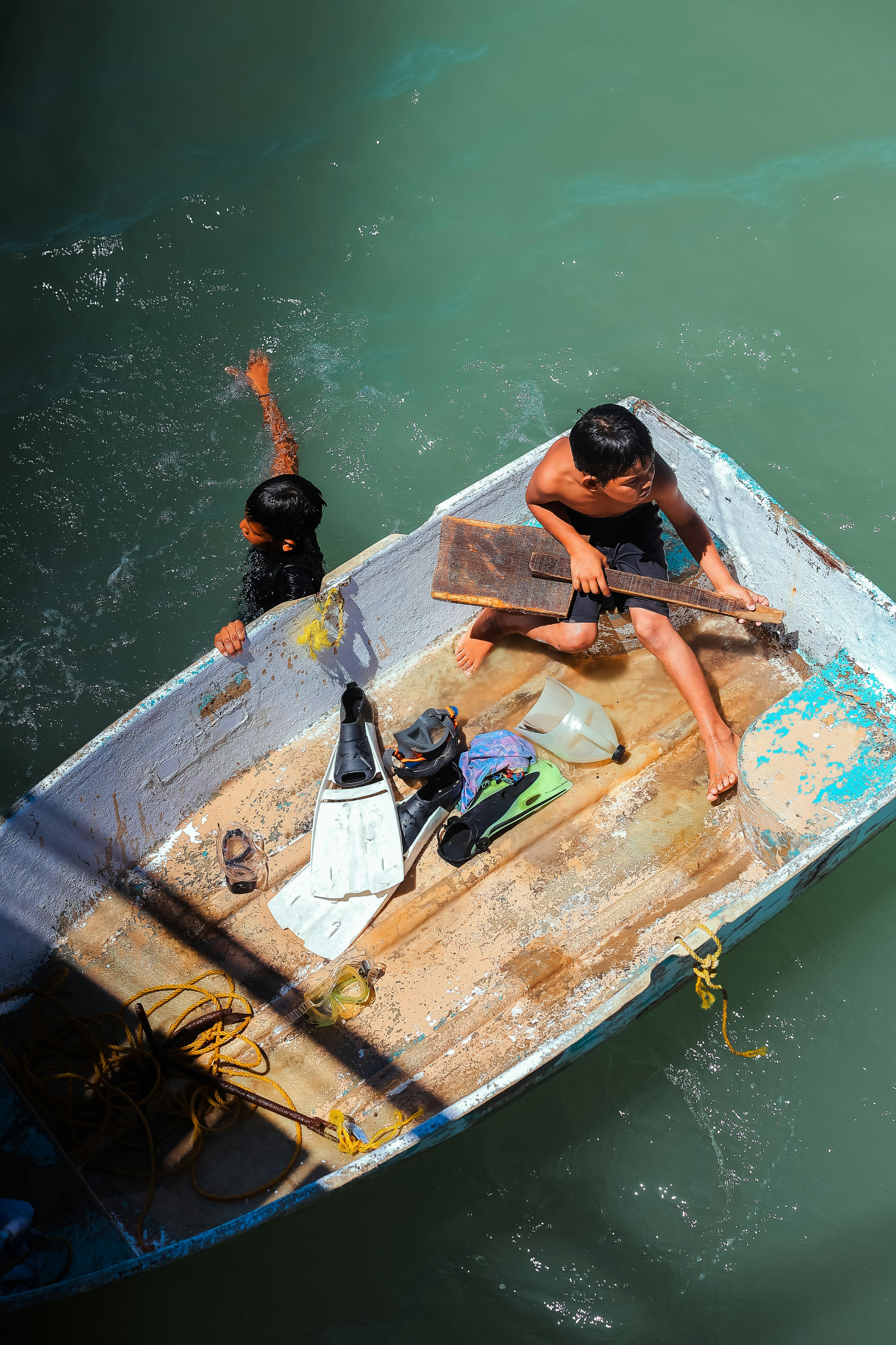 Two children playing on a small wooden boat in the waters of Bahía de Kino, Sonora, Mexico on a sunny day.