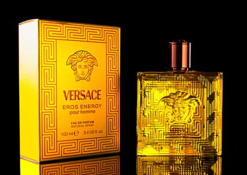 Free Intricately designed Versace Eros Energy perfume bottle with matching box on a dark background. Stock Photo