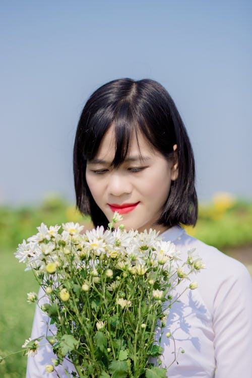 女人拿着白花的选择性焦点摄影