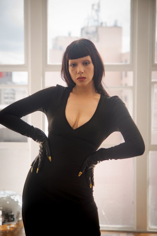 Free Chic woman in black dress poses confidently indoors with urban backdrop. Stock Photo