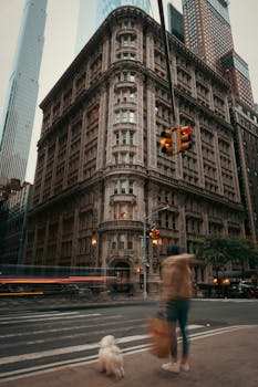 A historic building with intricate details captured in a busy city corner with a motion-blurred pedestrian and dog.
