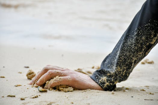 Close-up of a hand resting on sandy beach, capturing the serene and peaceful beach ambiance.