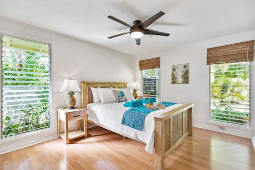 这间阳光明媚的热带卧室配有木制家具、茶绿色点缀和郁郁葱葱的绿色景观