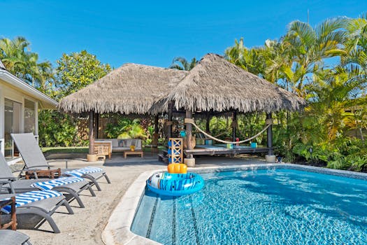 Relax by a luxurious poolside with beach chairs and a thatched bungalow.
