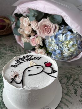 Birthday cake with artistic icing design and floral bouquet background, perfect for celebrations.