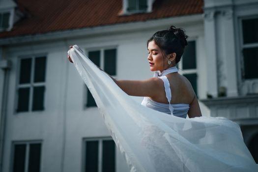 A graceful Indonesian dancer in white attire poses elegantly outdoors in Jakarta.