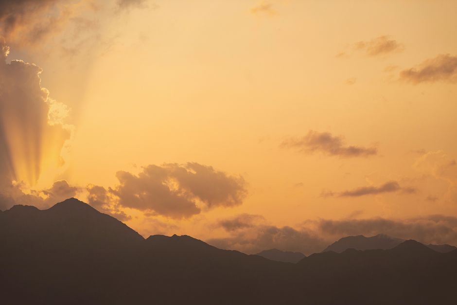 Beautiful sunset over Omani mountains with dramatic sunrays piercing through clouds.