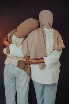 Two women in hijabs sharing a warm embrace, showcasing friendship and cultural fashion.