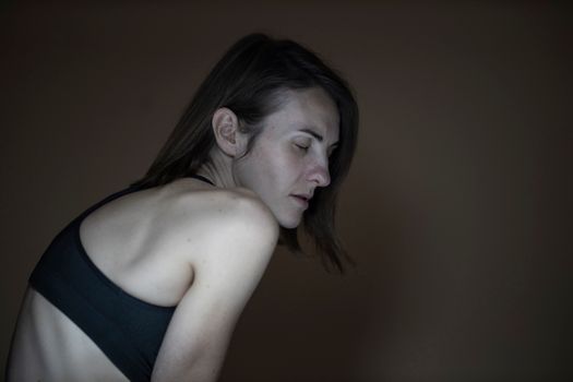 一张在低光下拍摄的、闭眼沉思的女人肖像