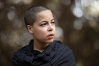 一个短发女人在模糊的户外背景中，神情显得很体贴