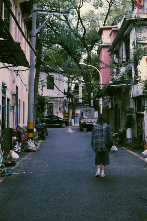 Free A person walking alone on a quiet urban street lined with trees and buildings. Stock Photo