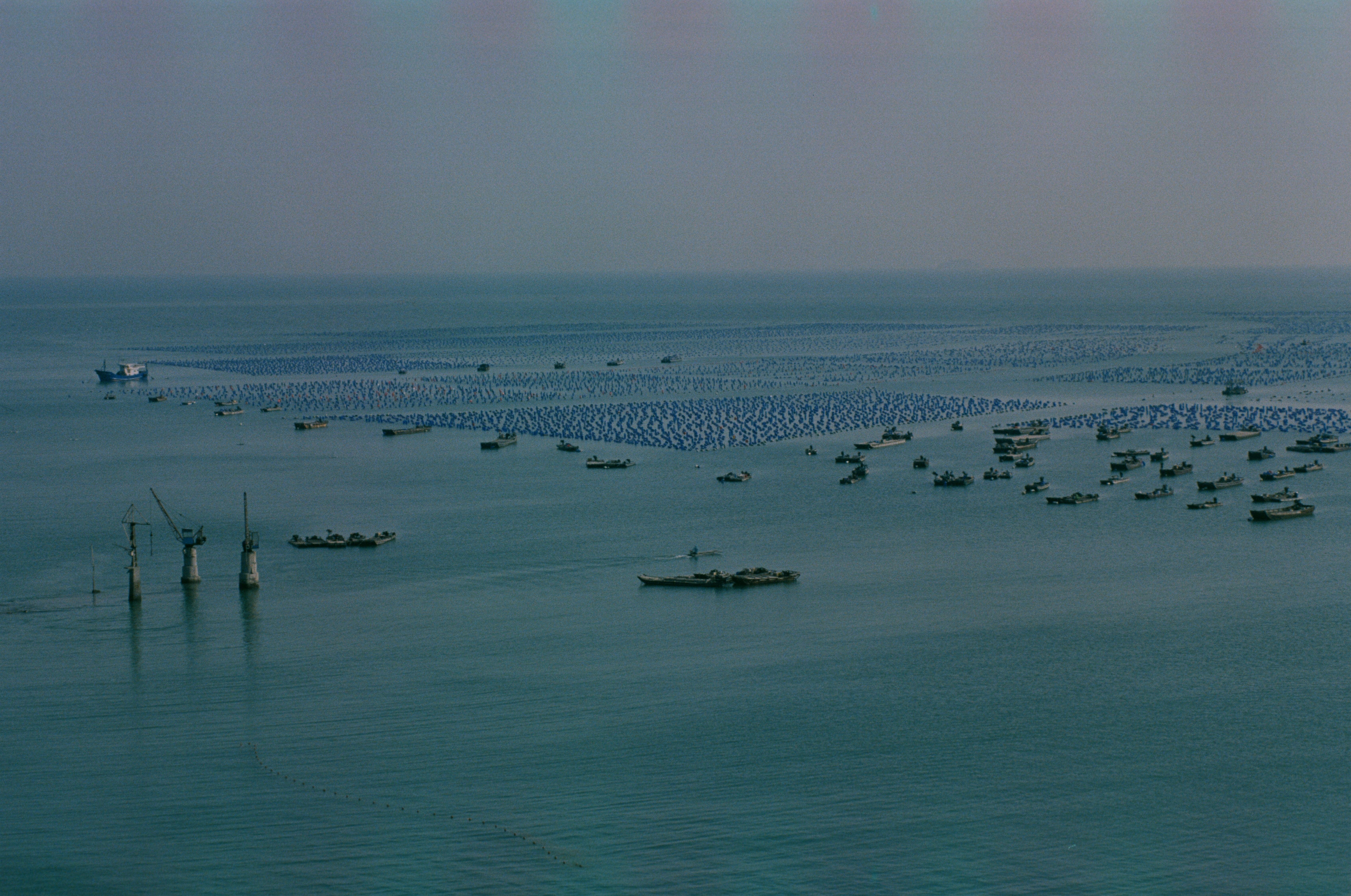 Aerial shot of multiple fishing boats and structures in a vast open sea, depicting a serene marine landscape.