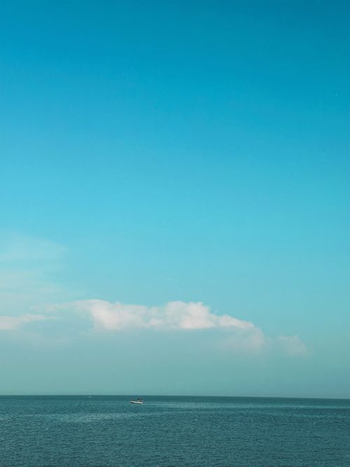 Free Tranquil ocean scene with a vast blue sky and gentle clouds. Stock Photo