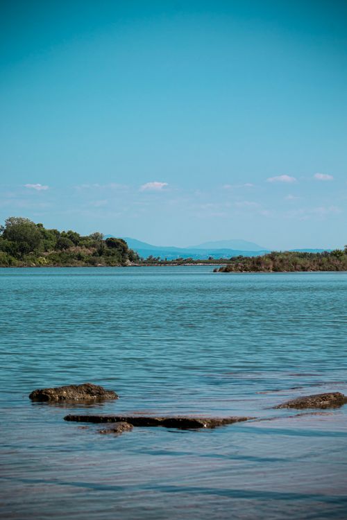 Free Peaceful lake scene with clear blue sky and distant hills in Friuli-Venezia Giulia. Stock Photo