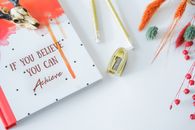 Inspirational flat lay featuring a motivational notebook and stylish stationery on a white background.