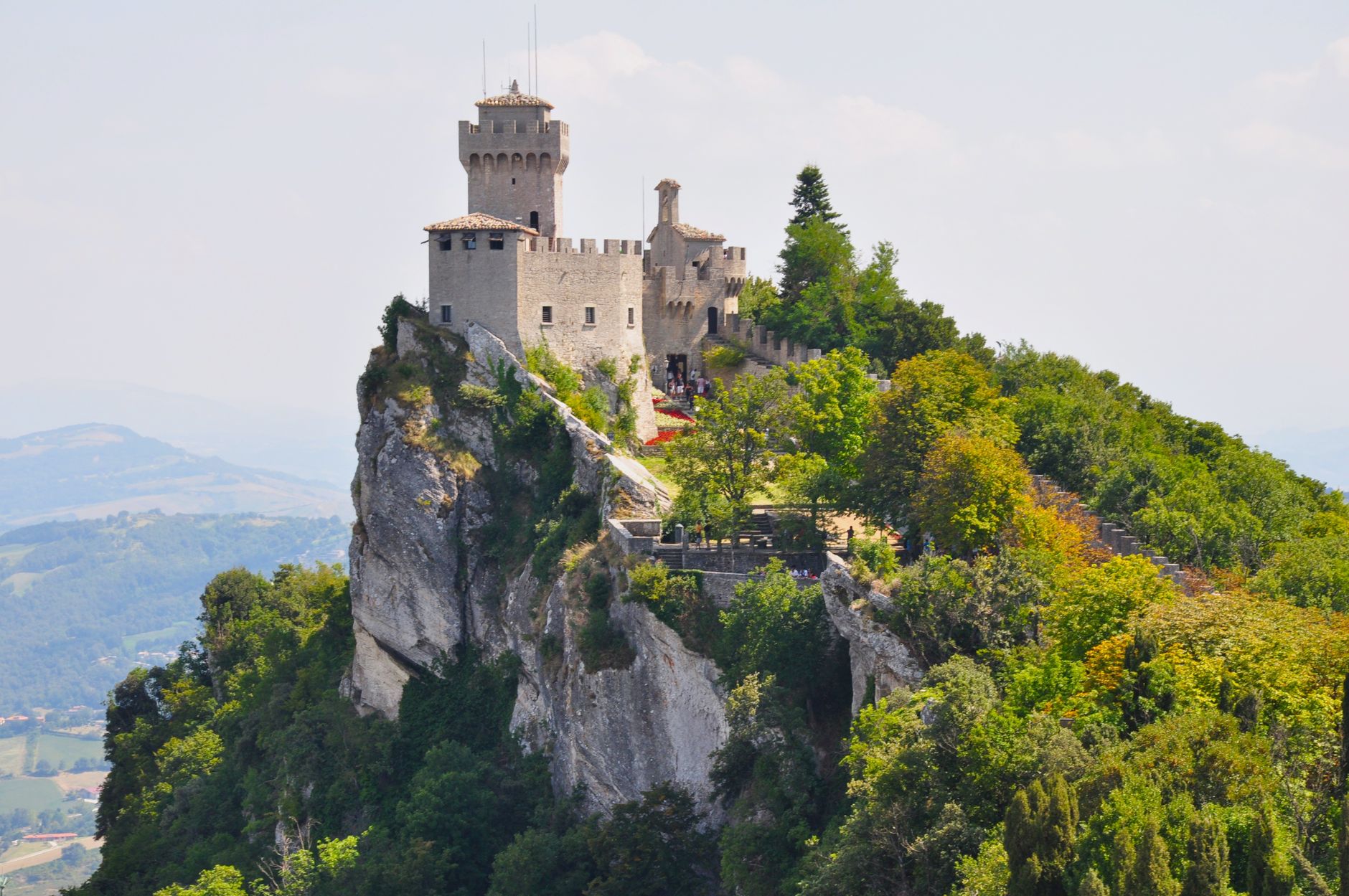 Explore San Marino's Guaita Castle perched on a stunning rocky hill surrounded by lush greenery.